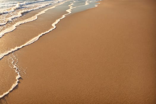 The image is a sandy beach with waves crashing against the shore.