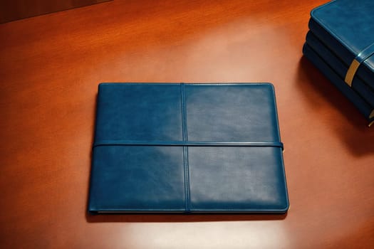 The image is a blank notebook with a blue cover and a pen on top of it.
