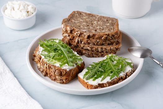 Sandwiches with curd cheese and arugula. Rye bread with seeds.