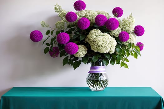 The image shows a vase filled with pink and white flowers on a blue tablecloth.