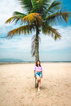 Brazilian Woman posing at a palmtree at the beach of Santos, Brazil.
