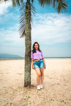 Brazilian Woman posing at a palmtree at the beach of Santos, Brazil.