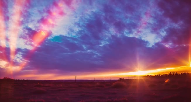 The image shows a sunset over a field with clouds in the sky.