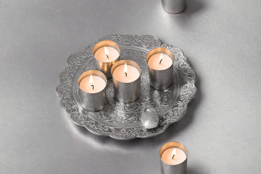 The image shows a silver tray with three white candles on it.