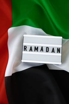 RAMADAN text frame on United Arab Emirates waving flag made from silk material. Public holiday celebration background. Commemoration Day Muslim The National Flag of UAE. Patriotism Blessed Holy Month concept