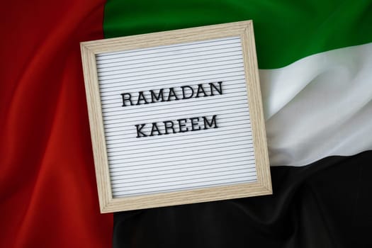 Congratulations with text RAMADAN KAREEM - happy holidays waving UAE flag on background concept. Greeting card advertisement. Commemoration Day Muslim Blessed holy month public holiday