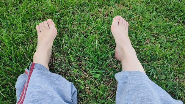 bare feet, gray trousers, green grass. High quality photo