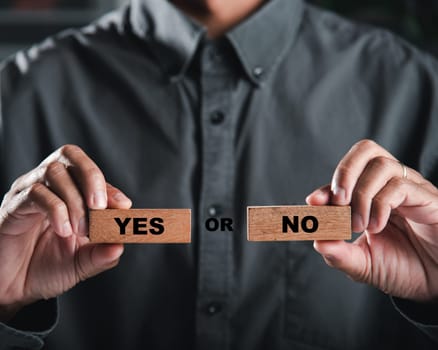 Wooden blocks held by businessman hands display yes and no choices indicating decision-making. Symbolic signs for business success. Think With Yes Or No Choice.