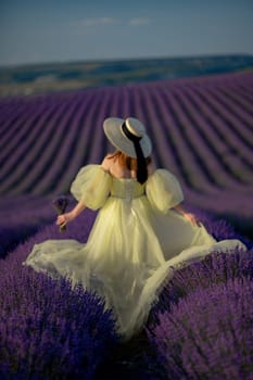 Back view woman lavender sunset. Happy woman in yellow dress holds lavender bouquet. Aromatherapy concept, lavender oil, photo session in lavender.