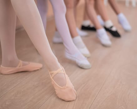 Close-up of feet of 5 little girls and teacher at ballet class