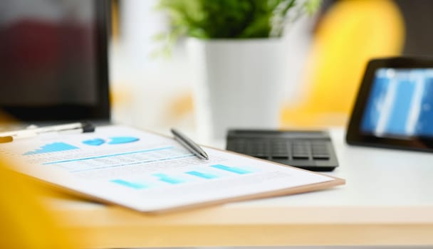 Silver pen lying on important stats paper clipped to pad at table workspace in office closeup. Trade result form paperwork job bank credit loan balance invest payment irs currency audit budget trend