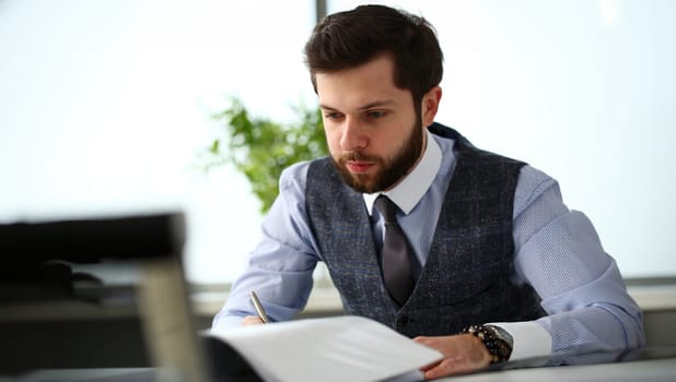 Handsome smiling bearded clerk man at office workplace with silver pen in arms do paperwork portrait. Staff dress code worker job offer client visit study profession boss market idea coach training