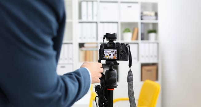 Male arms in suit mount camcorder to tripod making promo videoblog or photo session in office closeup. Vlogger adjust set up and check image quality to show job offer promotion selfie information