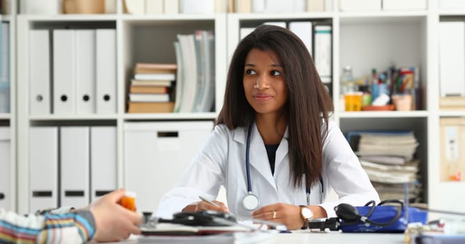 Female medicine doctor hand hold jar of pills and write prescription to patient at worktable. Panacea and life save, prescribing treatment, legal drug store concept. Empty form ready to be used