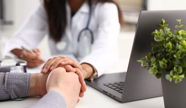 Friendly female doctor hold male patient hand in office during reception. Examination result positive test calm down promise and cheer up grief and suffer treatment condolence ethics concept