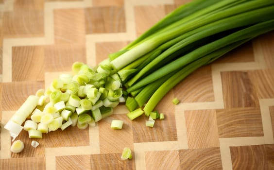 Cuts on cutting board green onions for salad or fresh vegetable soup with vitamins. Raw food and vegetarian recipe book in modern society popular concept.