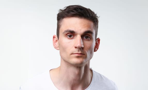 Fitness man portrait cute in a white tank top on a gray background smiling and looking at the camera fashion industry model