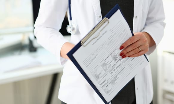 Female doctor hand holding and filling patient history list at clipboard pad during physical. Exam er disease prevention ward round visit check 911 prescribe remedy healthy lifestyle concept.