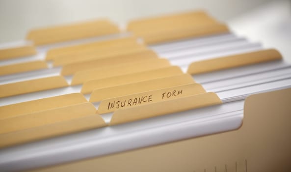 Yellow folders with labels and paper in a row in the insurance file closeup