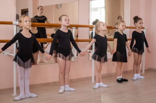 Children's ballet school. Caucasian woman teaching ballet to little girls