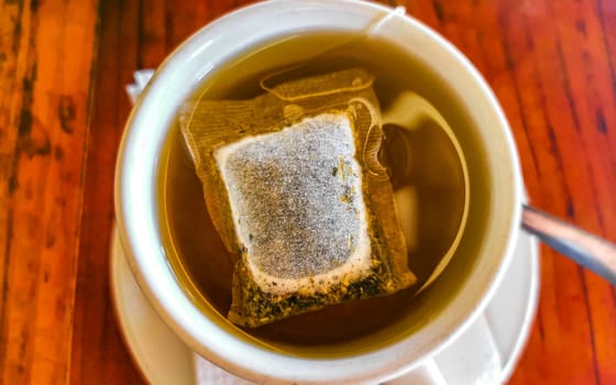 White cup of tea with tea bag on wooden table in Zicatela Puerto Escondido Oaxaca Mexico.