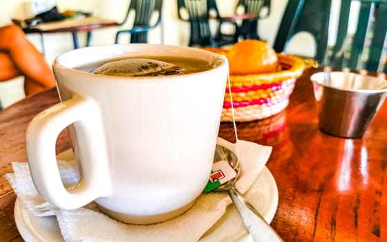 White cup of tea with tea bag on wooden table in Zicatela Puerto Escondido Oaxaca Mexico.