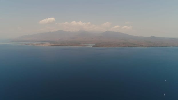 aerial coast of the island from the sea. seascape sea surface against mountains. Flying over the azure surface ocean. Travel concept