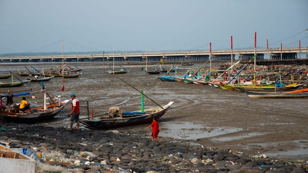 Harbor at low tide with fishing boats waiting high tide. fishing boats in dry harbour at low tide