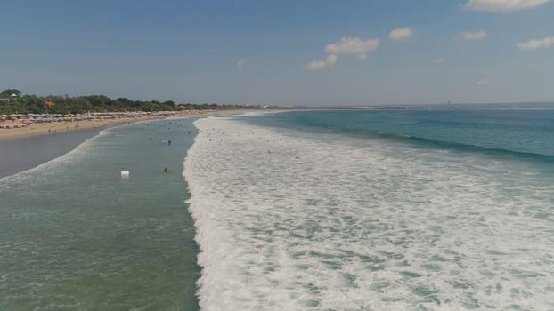 Aerial view sand beach with surfers and tourists, Kuta, Bali. surfers on water surface ocean catch wave. Seascape, beach, ocean, sky sea Travel concept