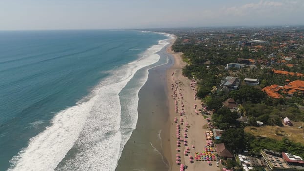 Aerial view sand beach with resting people, hotels and tourists, sun umbrellas, Bali, Kuta. surfers on water surface. Seascape, beach, ocean, sky sea Travel concept