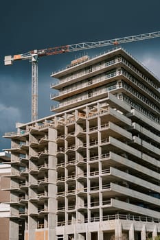 Tower crane above an apartment building under construction against a stormy sky. High quality photo