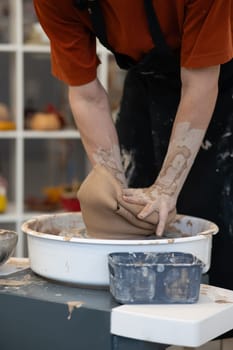 Close-up of a man's hands breaking a ceramic vase on a potter's wheel. School of Ceramics. Vertical photo