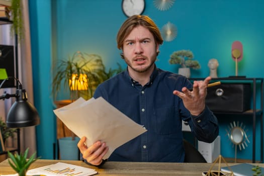 Conflict quarrel negotiation. Portrait of angry young businessman engaged in webcam online video call at home office. Upset freelancer guy discussing conversation after analyzing financial report.