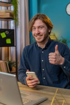 Businessman using smartphone app online pointing showing like thumbs up remote distance job working from home office. Man freelancer guy e-learning texting messages content on social media. Vertical
