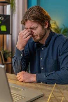 Bored sleepy sick businessman worker working on laptop computer, rubbing eye pinch nose at home office desk. Exhausted tired Caucasian freelancer workaholic guy. Employment, occupation, workless