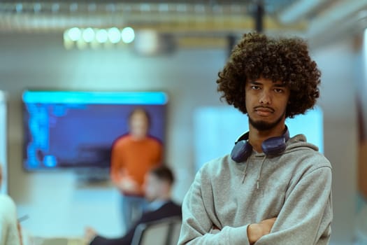 In a modern office environment, an African American young entrepreneur with headphones engages in work, while in the background, his dedicated colleagues exemplify teamwork and collaboration, encapsulating the essence of contemporary corporate success.