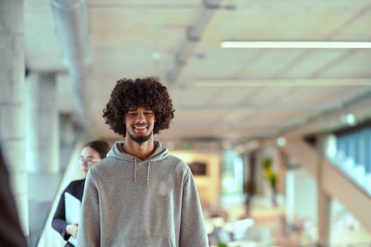 In a modern office environment, an African American young entrepreneur engages in work, while in the background, his dedicated colleagues exemplify teamwork and collaboration, encapsulating the essence of contemporary corporate success.