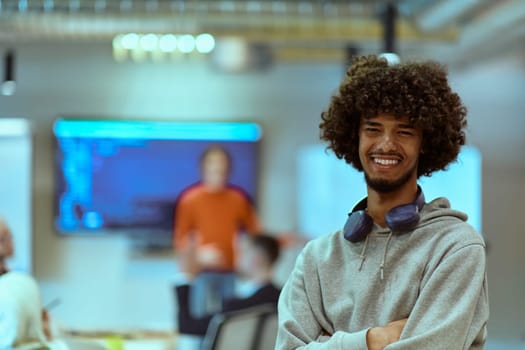 In a modern office environment, an African American young entrepreneur with headphones engages in work, while in the background, his dedicated colleagues exemplify teamwork and collaboration, encapsulating the essence of contemporary corporate success.