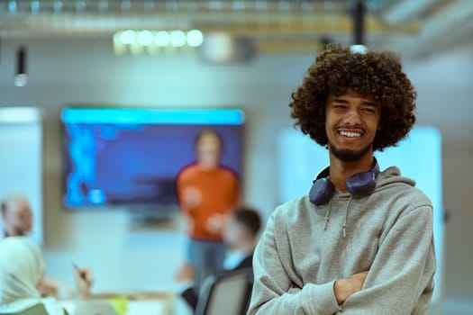 In a modern office environment, an African American young entrepreneur with headphones engages in work, while in the background, his dedicated colleagues exemplify teamwork and collaboration, encapsulating the essence of contemporary corporate success.