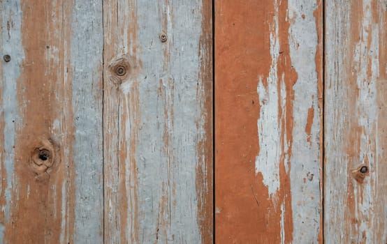 Detailed closeup of a brown hardwood plank fence with peeling wood stain and varnish, showcasing the natural materials pattern and texture