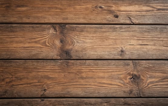 A closeup of a brown hardwood table with a wooden background. The table is made of rectangular planks with a beautiful wood stain pattern