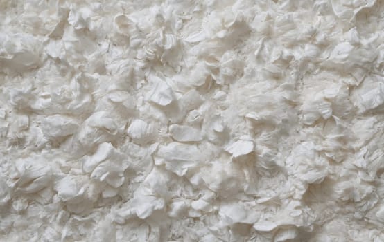 A close up of a pile of white foam resembling limestone on grey flooring, surrounded by beige wood, grass, soil, and rocks, creating a unique pattern