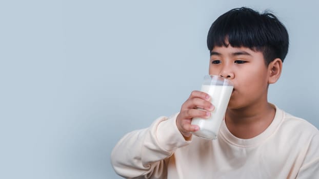 Concept of happy good nutrition, Portrait of a little young handsome kid boy in cream color shirt, Hold drinking milk box mockup, Isolated on white background.