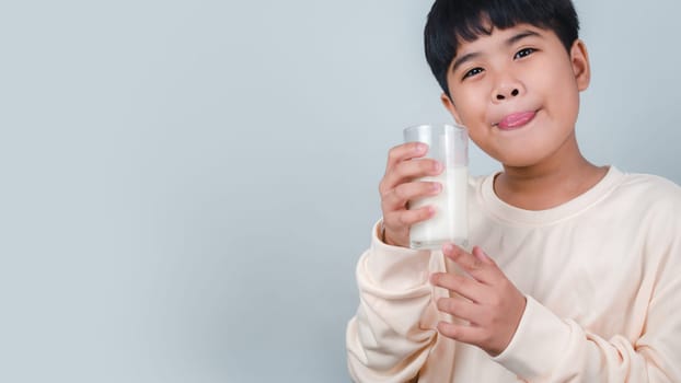 Concept of happy good nutrition, Portrait of a little young handsome kid boy in cream color shirt, Hold drinking milk box mockup, Isolated on white background.