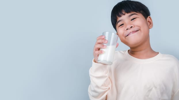 Concept of happy good nutrition, Portrait of a little young handsome kid boy in cream color shirt, Hold drinking milk box mockup, Isolated on white background.