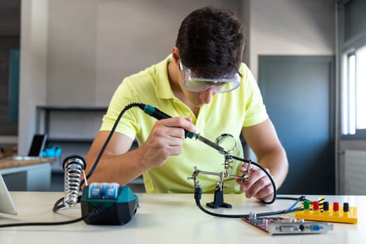 Caucasian male high school student in electronics class working on a project alone.Education concept.