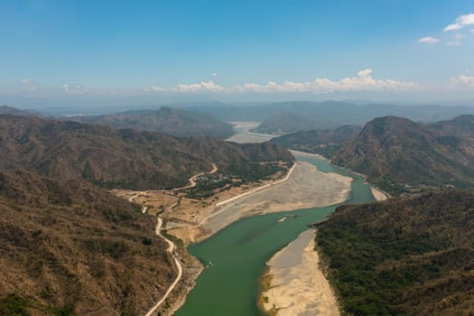 Aerial drone of river flowing in a valley among the mountains. Mountain landscape. Luzon, Philippines.