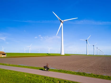 A picturesque scene of a wind farm in Flevoland, Netherlands, with multiple towering windmills rotating in the Spring breeze. windmill turbines, green energy, eco friendly, earth day