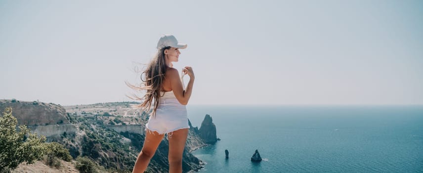 Woman travel sea. Young Happy woman in a long red dress posing on a beach near the sea on background of volcanic rocks, like in Iceland, sharing travel adventure journey