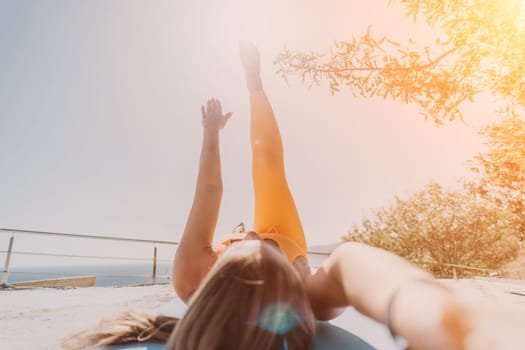 Fitness woman sea. Outdoor workout on yoga mat in park near to ocean beach. Female fitness pilates yoga routine concept. Healthy lifestyle. Happy fit woman exercising with rubber band in park.